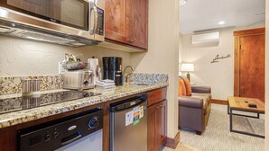 Cocina compacta con microondas, tostadora, cafetera y lavavajillas. Hay una pequeña zona de estar con sofá y mesa.