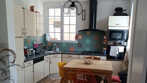 A kitchen with a dining table, chairs, and a stove. - Maison de Ville Avec Terrasse de 30 m2, Proche des Transports en Commun et Paris (Pomponne)