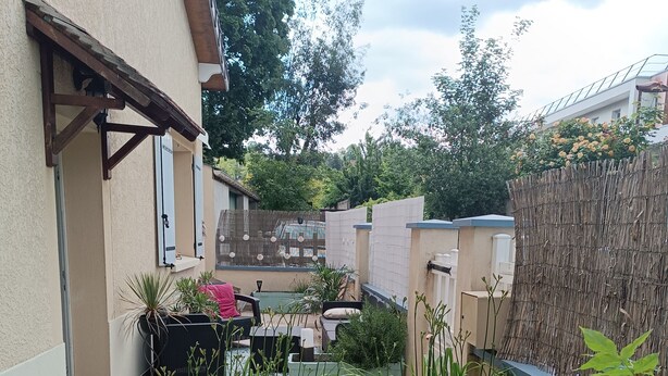 A small, enclosed garden area with a patio table and chairs, surrounded by various potted plants and a bamboo fence. - Maison de Ville Avec Terrasse de 30 m2, Proche des Transports en Commun et Paris (Pomponne)
