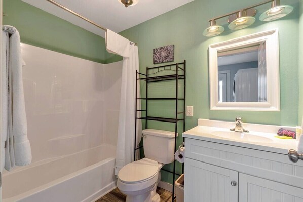 Un baño con ducha, inodoro y lavabo con espejo.