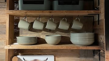 Une cuisine avec des étagères en bois où sont rangés divers ustensiles, notamment des casseroles, des bols et un grille-pain.