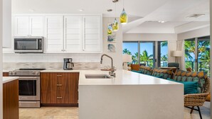 A modern kitchen with white cabinets, stainless steel appliances, and a large island.