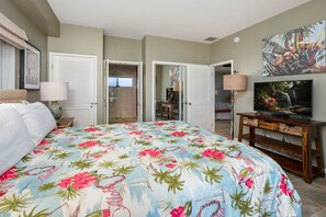 A bedroom with a large bed, a TV, and a wooden nightstand.