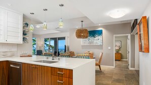 A modern kitchen with wooden cabinets, a large island, and pendant lighting.
