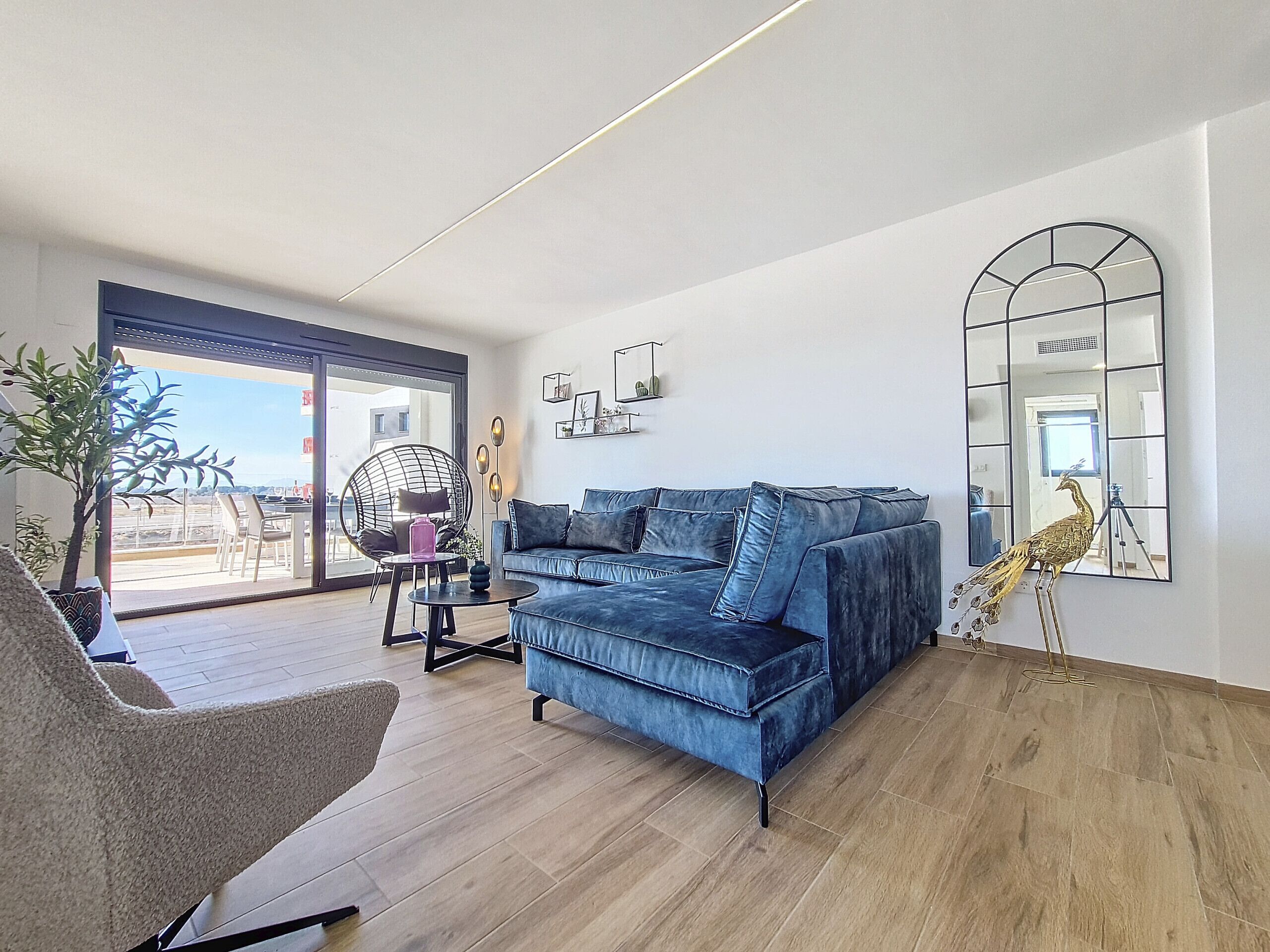 A modern living room with a blue sofa, a round chair, and a large mirror on the wall.