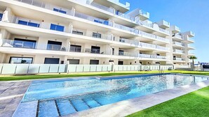 Un hotel moderno de varios pisos con una piscina en primer plano.
