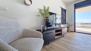 Una sala de estar moderna con un sofá, un televisor y una planta en maceta.