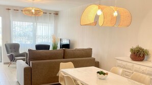 Ein modernes Wohnzimmer mit einer Couch, einem Esstisch, Stühlen und einem Fernseher.