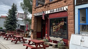 A brick building with a sign reading "The Enterprise Bar & Grill" and a vintage sign above the entrance. - Lawless: A Boutique Basecamp in Rico (Rico)