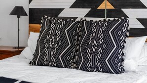 A bed with a patterned pillow and a blanket, a wooden headboard with a geometric design, and a nightstand with a lamp. - Lawless: A Boutique Basecamp in Rico (Rico)