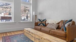 A living room with a brown sofa, patterned cushions, and a wooden bench. - Lawless Rico: Enterprise Suite (Rico)