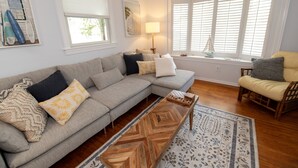 A living room with a sectional sofa, a wooden coffee table, a patterned rug, a chair, and a window with blinds. - NEW LISTING!!! Cedar Shade Beach Retreat (Lower Township)