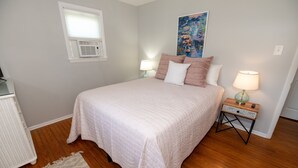 A bedroom with a bed, bedside lamps, a painting, and an air conditioning unit. - NEW LISTING!!! Cedar Shade Beach Retreat (Lower Township)