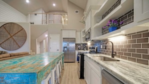 A kitchen with a wooden island, white cabinets, a stainless steel refrigerator, and a brick backsplash. - Pool Access + Boat Dock Steps to the Gulf The Pintail by Avantstay (Corpus Christi)