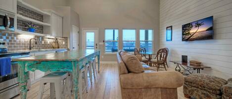 A spacious living area with a kitchen, a large window with a view, and a cozy seating arrangement.