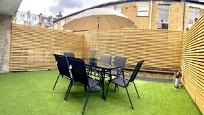 A patio area with a table and chairs, a wooden fence, and a brick building in the background. - NEW LISTING!!! Fantastic location for discovering London (London)