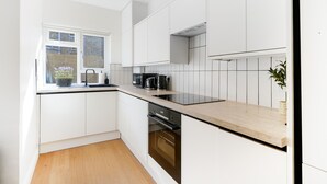 A modern kitchen with white cabinetry, a black countertop, and a window with blinds. - NEW LISTING!!! Fantastic location for discovering London (London)