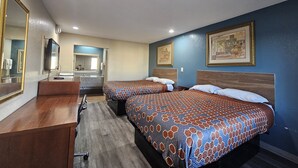 Habitación de hotel con dos camas, un escritorio, un espejo y un baño al fondo.