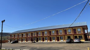 Un motel de varios pisos con techo plano, múltiples habitaciones y un estacionamiento.