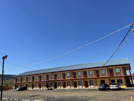 Un motel de varios pisos con techo plano, múltiples habitaciones y un estacionamiento.