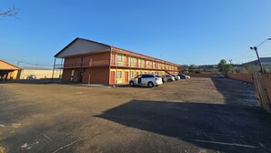 Un motel con varias habitaciones, un estacionamiento y cielo despejado.