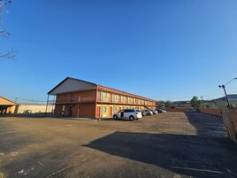 Un motel con varias habitaciones, un estacionamiento y cielo despejado.