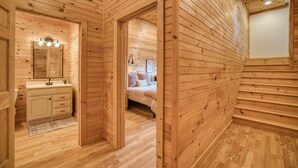 Ein Holzblockhaus innen mit Bad, Schlafzimmer und einer Treppe.