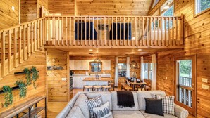 Ein Holzblockhaus-Interieur mit Essbereich, Küche und einem Balkon.