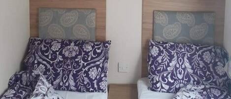 Two twin beds with patterned bedding, wooden headboards, and a small bedside table.