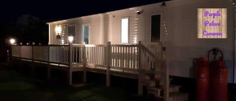 Un bâtiment d’un seul étage, doté d’une terrasse en bois et d’une enseigne au néon sur laquelle on peut lire : « Purple Palace Caravan ».