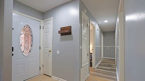 A hallway with a welcome sign, a door with a stained glass window, and a staircase leading to another room.