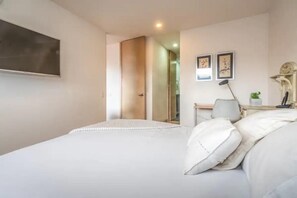 Relax in a serene space with a large bed, flat-screen TV, and a convenient desk area.