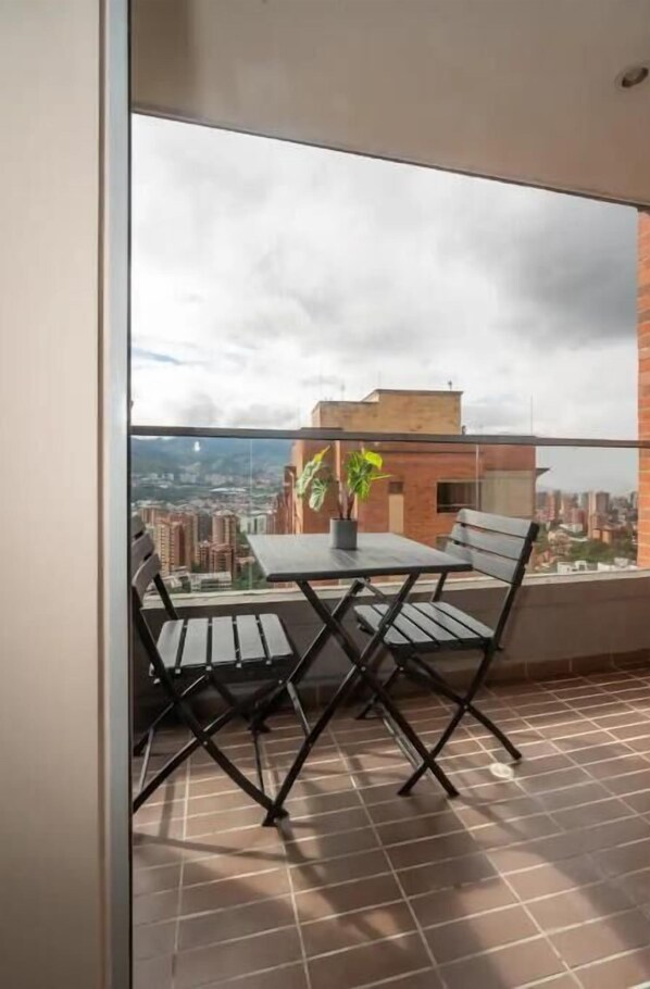 Enjoy a city view from this balcony with a foldable table and chairs, perfect for dining or relaxing.