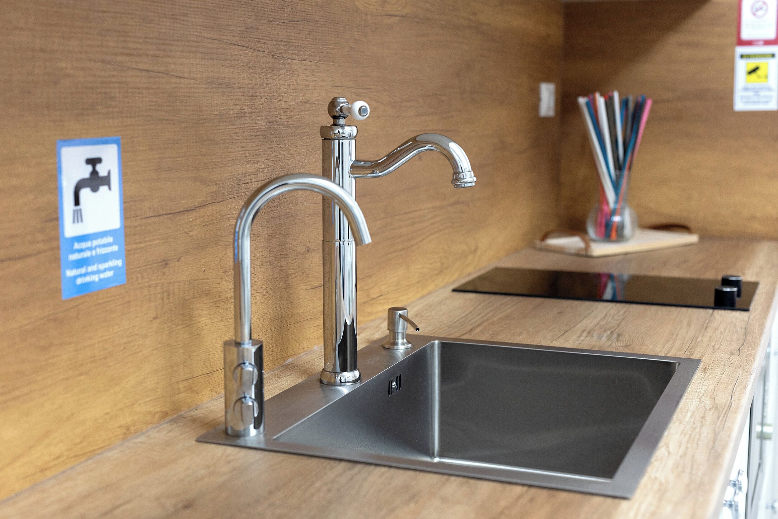 Eine moderne Küche mit Spüle aus Edelstahl, einem Wasserhahn und einer Holz Arbeitsplatte.