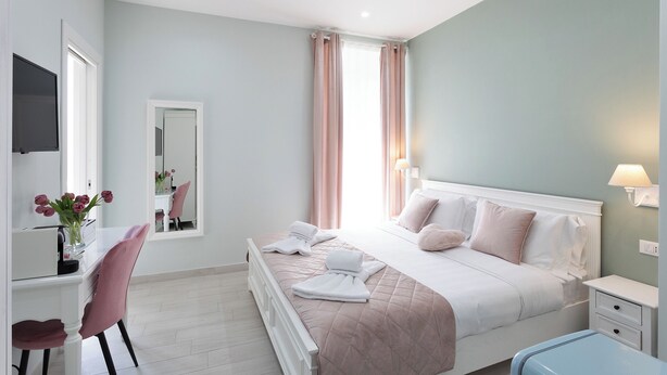A bedroom with a bed, bedside table, lamp, and a desk with a chair. - Colosseo House (Rome)