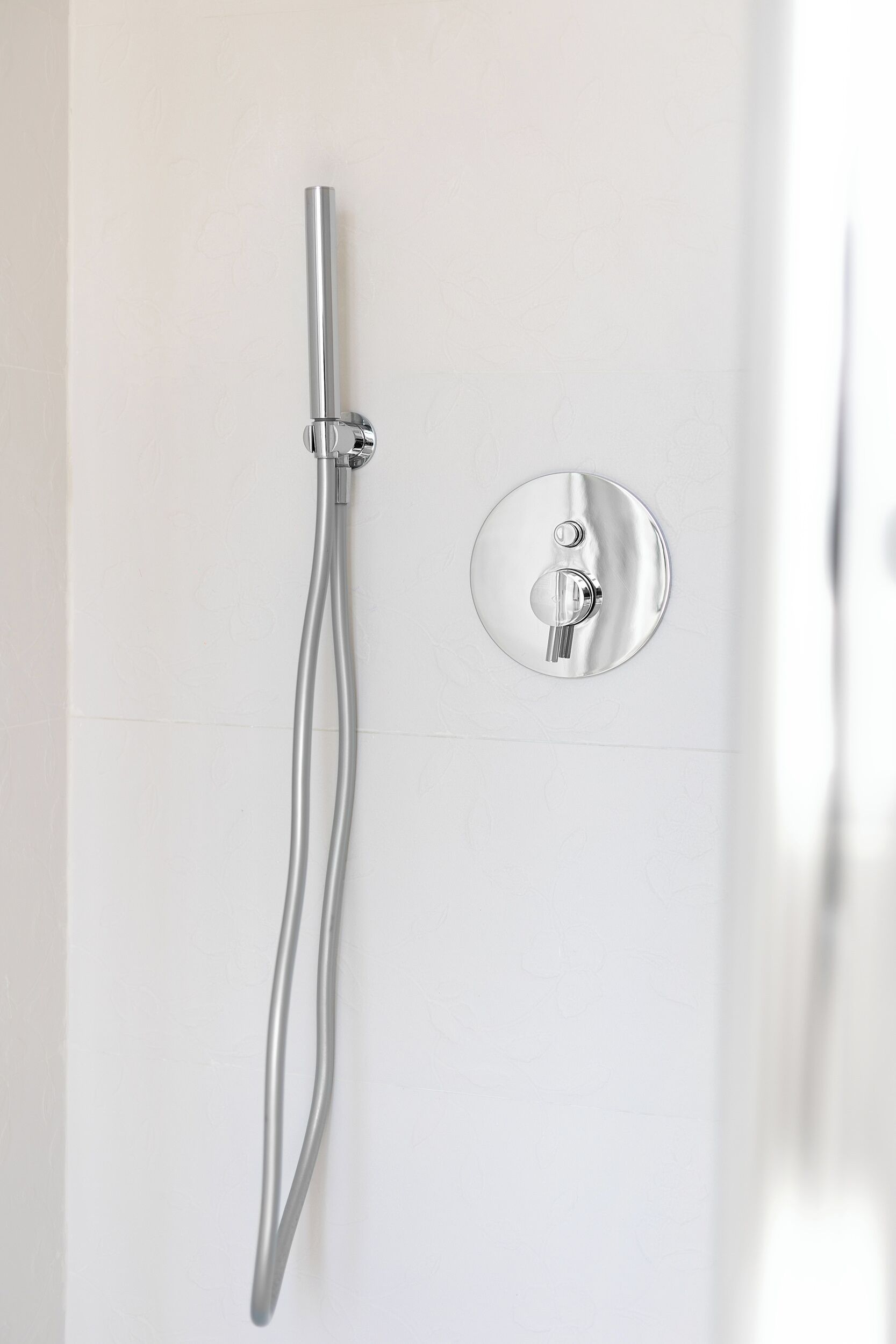 A modern bathroom with a wall-mounted shower and a control panel.
