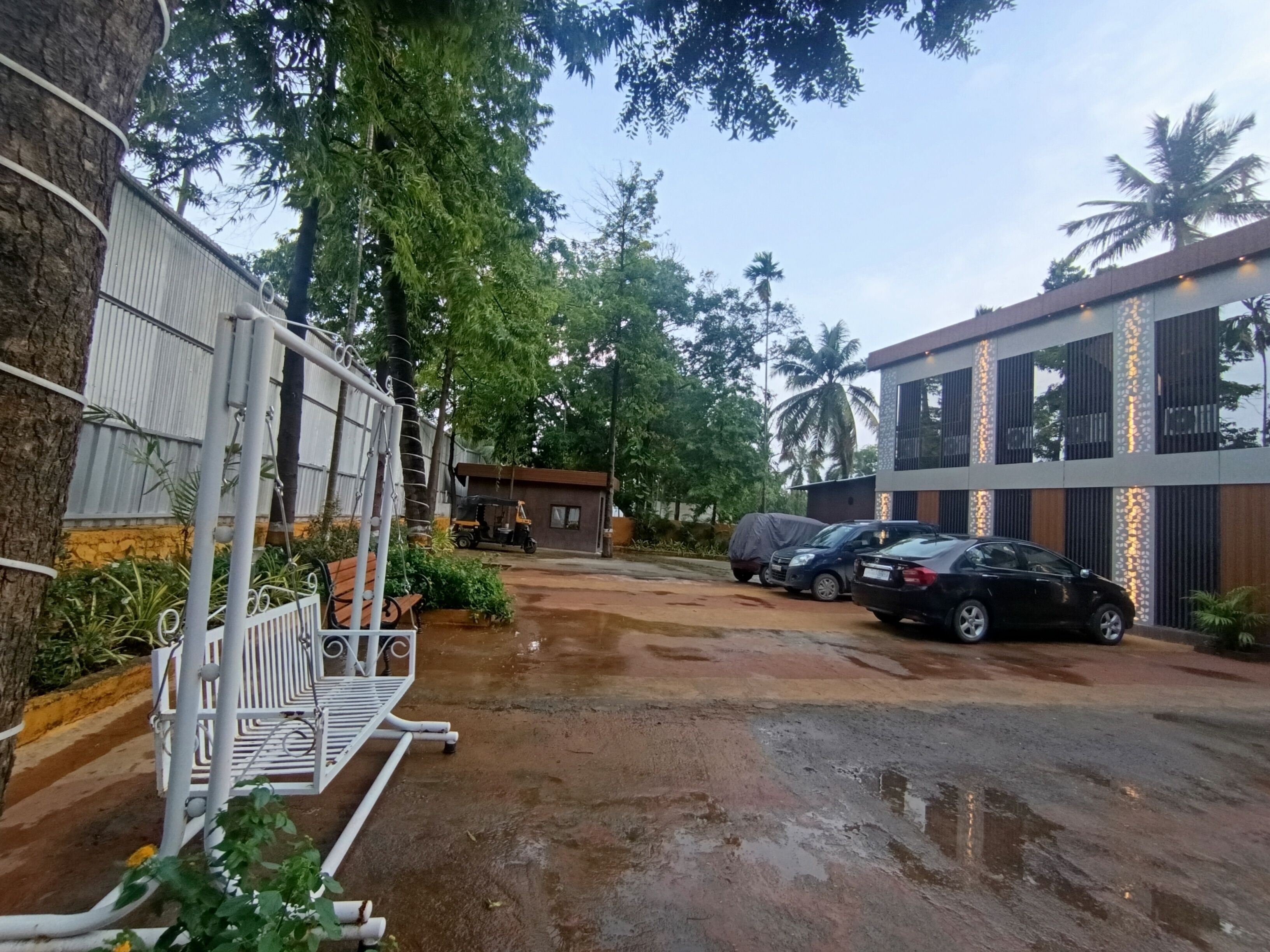 Uma área de estacionamento com um carro coberto, um banco e um edifício com tiras de luz verticais.