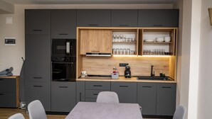 A modern kitchen with grey cabinets, a wooden countertop, and a built-in wine rack. - Luxury villa in the heart of Rila mountain. The only one 103 deg mineral spring (Sapareva banya)