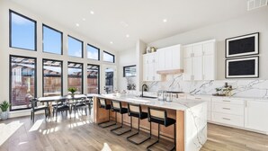 Una cocina moderna con ventanas amplias, una isla central y armarios blancos.