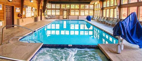 A wooden interior with a pool, benches, and a hot tub.