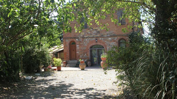 A courtyard with a brick building, potted plants, and a pathway. - In the heart of Valdichiana historic Tuscan farmhouse, swimming pools for exclusive use (Toscana)