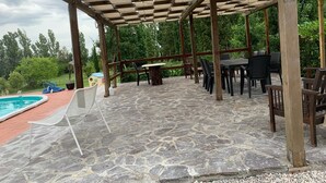 A covered patio area with stone flooring, outdoor furniture, a pool, and a view of greenery. - In the heart of Valdichiana historic Tuscan farmhouse, swimming pools for exclusive use (Toscana)