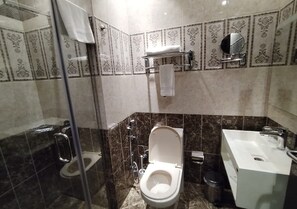 A bathroom with a toilet, bidet, glass shower enclosure, and a sink with a mirror. - Sansa Hotel (Jeddah)