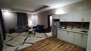 A compact hotel room with a kitchenette, a seating area with a sofa and a coffee table, and a patterned rug. - Sansa Hotel (Jeddah)