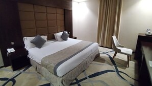 A hotel room with a large bed, a desk, a chair, and a nightstand. - Sansa Hotel (Jeddah)
