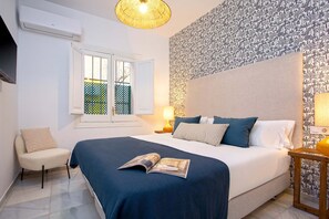 A bedroom with a bed, a chair, a window, and a wall with a patterned wallpaper. - Genteel Home Baños IV (Seville)