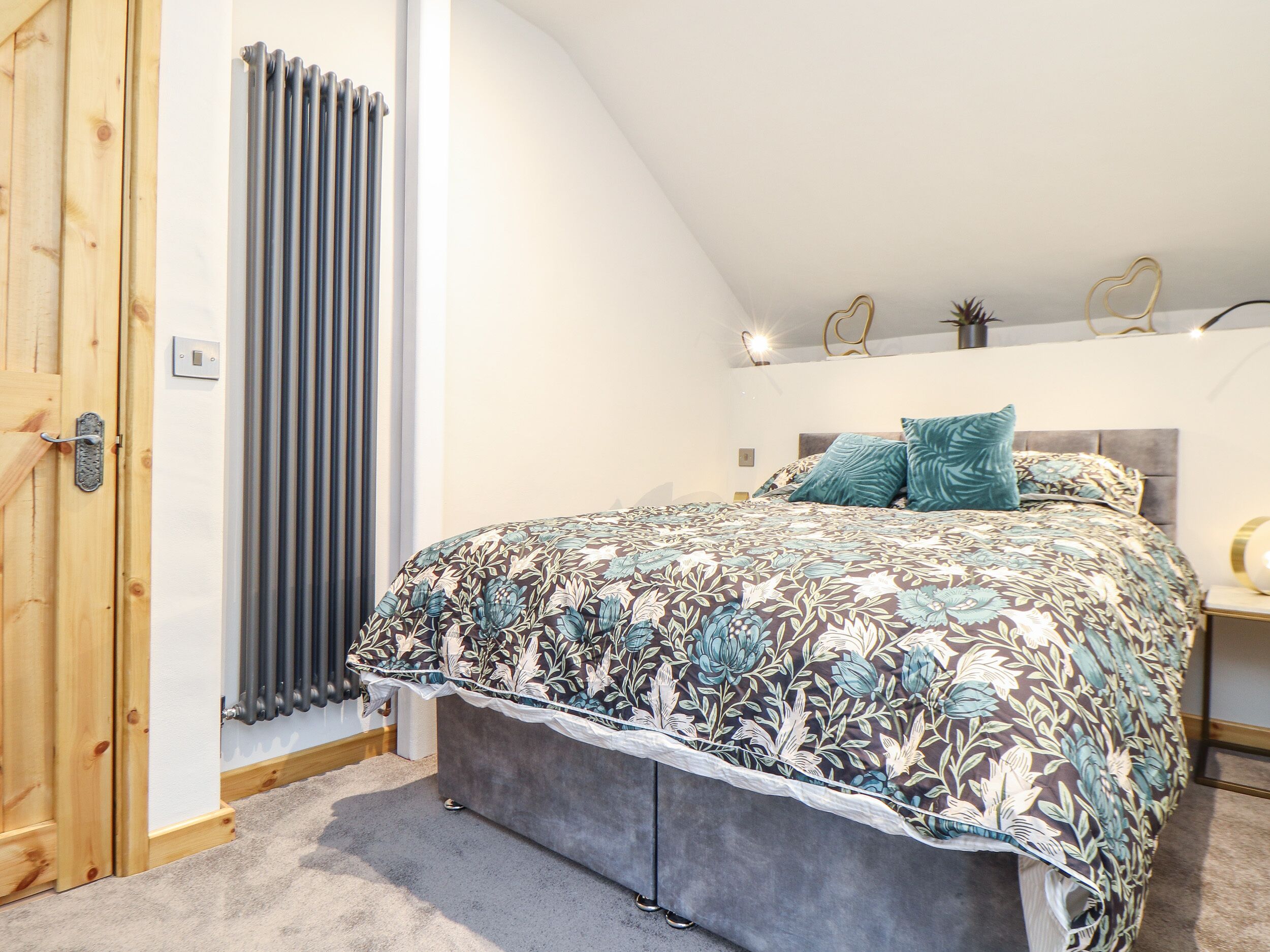 Une chambre à coucher avec un lit, un radiateur, une porte en bois et une table de chevet avec une lampe.