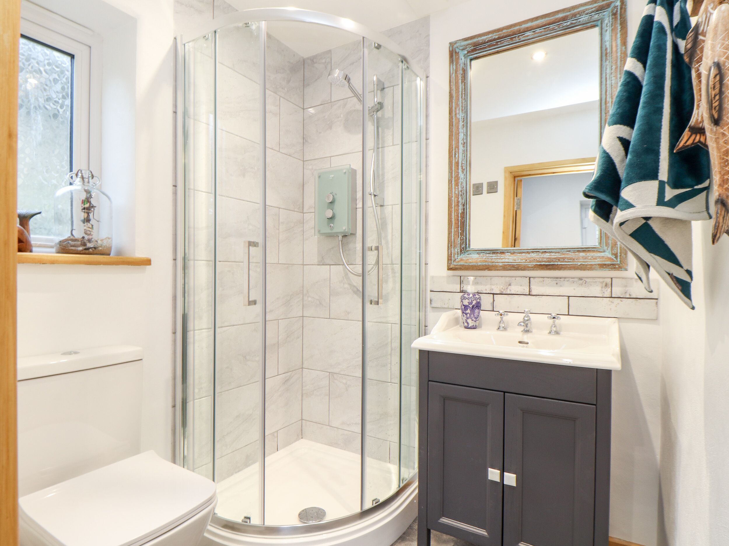 A modern bathroom with a glass-enclosed shower, a white toilet, a sink with a mirror, and a cabinet.