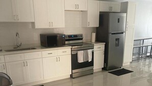A modern kitchen with white cabinets, a stainless steel refrigerator, a microwave, and an oven. - Apartment Sleeps 6 With Pool Access (Portmore)