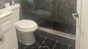 A bathroom with a toilet, a shower enclosure, and a sink. - Apartment Sleeps 6 With Pool Access (Portmore)